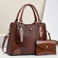 Detail of dark brown crocodile pattern patent leather tote bag with gold metal rivets - Brown