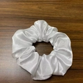 Detailed view of a white satin LED hair scrunchie placed on a wooden surface - White [three-level Headlights]