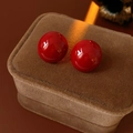 Detalle de pendientes de bola rojos brillantes sobre un joyero de terciopelo marrón oscuro - Color Sólido / Poste de pendiente de plata - Rojo