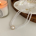 Macro detail of a double-layer pearl necklace with a sparkling diamond pendant flower design - Double Layer Pearl Round Pendant Necklace / White