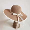 Dettaglio del cappello di paglia da donna con trama intrecciata e fiocco in pizzo bianco - Taglia unica / Cachi
