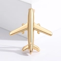 Golden airplane metal brooch pin displayed on white props for elegant suit accessories - Gold