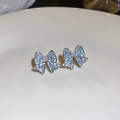 Macro shot of silver butterfly stud earrings with light blue crystals on a beige plate - 925 Sterling Silver Earring Post Silver Blue Ice Bowknot Style