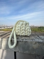 Detailansicht der grob gestrickten Samt-Schultertasche in Cremeweiß auf Beton im Freien - Milchweiß