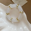 Detail of white marble resin segments and gold metal rings on an elastic bracelet - White