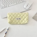Quilted cosmetic bag with diamond patterns on a desk near a laptop and stationery - Bright yellow