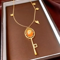Macro shot of vintage gold key necklace with orange gemstone and floral details - Necklace - Gold
