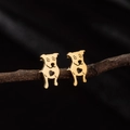 Close-up of golden hollow dog and heart shaped stainless steel stud earrings on a twig - Gold