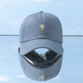 Detail view of light blue daisy embroidery on cotton baseball cap with mirror reflection - Blue