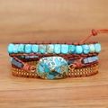 Boho multi-layer wrap bracelet with turquoise stones and gold chain on wood background - Bohemian Multilayer Turquoise Style