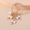 Detail of four dragonfly and flower alloy pendants on a light gold keychain hook - White