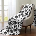 Detail of cow print flannel blanket draped on a chair showing soft texture and pattern - Style 55 (Black & White Cow Print)