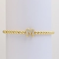 Close-up of golden beaded stretch bracelet with micro-paved zircon letter M pendant - M