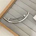 Elegante pinza para el cabello plateada con diseño curvo sobre bandeja de terciopelo gris - Plateado