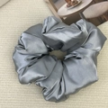 Close-up of a silver-grey oversized satin scrunchie showing glossy silk texture and folds - Blue