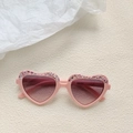 Détail de lunettes de soleil cœur rose pour enfants avec paillettes sur tissu texturé - Gris rosé