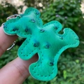 Close-up of green PU leather bear keychain with ostrich texture held in hand - Green