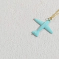 Light blue airplane pendant necklace with a golden chain on a textured surface - Light Blue (XL2377)