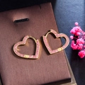 Detail von herzförmigen Goldohrringen mit rosa Zirkonia auf einer Schmuckschatulle - Goldrot