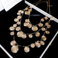 Détail d'un collier doré multicouche avec disques texturés dans un écrin noir élégant - Or (Ensemble de 3 pièces)