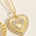 Dettaglio macro del ciondolo a cuore dorato con cristalli pavé e trama radiante su sfondo - Collana Doppio Cuore Zircone-Stile Trama Radiale