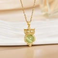 Macro detail of golden owl pendant featuring a centered green cat-eye gemstone - Gold Owl/Round Green Cat's Eye