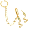 Detail of gold snake earrings with sparkling crystals, green gems, and chain link tassel - Snake