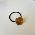 Élastique à cheveux fleur ambrée avec bande élastique noire sur fond blanc - Caramel
