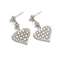 Macro shot of silver titanium heart earrings featuring hollow designs and clear crystal studs - Silver