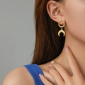 Golden crescent moon earrings with textured radial patterns worn by a model in profile - Gold Crescent Moon Pendant Style (E943-GO)