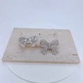 Boucles d'oreilles nœud argentées avec zircons présentées de face et de dos - Argenté