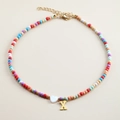 Detailed view of multi-color beaded necklace with a white heart and golden letter X pendant - Letter X
