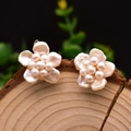 Baroque flower pearl stud earrings with golden alloy base on a rustic wood stand - White