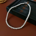 Detalle de collar de perlas elegante con cierre plateado sobre bandeja de exhibición - Gris-6mm