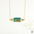 Dettaglio della collana a catena d'oro con ciondolo a cilindro smaltato e testo YOU - YOU/Nuvola/Verde Blu