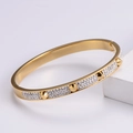 Gold plated nail bracelet with pavé rhinestones and conical studs on white wood stand - Gold