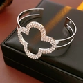 Macro detail of silver clover bracelet with sparkling rhinestones on black leather case - Clover Open Style / Silver