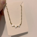 Detail of gold necklace with three white heart pendants on display card - Heart Style