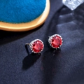 Macro shot of round red crystal stud earrings with silver claw setting on black background - Garnet Red 8MM