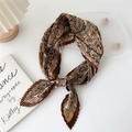 Brown pleated square scarf with paisley pattern tied in a knot on a white desk - Paisley Floral Border Caramel