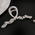 Macro detail of matte silver shark clip with colorful star and heart-shaped zircons - Crossed