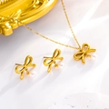 Primer plano detallado de un conjunto de collar y pendientes de lazo dorado con perlas - Juego