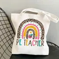 White canvas tote bag featuring a rainbow print and PE TEACHER text for sports teachers - Style C10