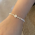 Macro-opname van kralenarmband met gouden letter X-bedeltje om de pols gedragen - Letter X Stijl (X)