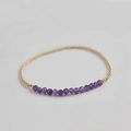 Detailed macro view of amethyst faceted beads and golden metal spacers on elastic bracelet - Amethyst