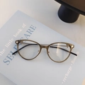 Montatura rotonda verde oliva con stanghette in metallo dorato su un libro azzurro - Verde Trasparente