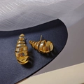 Elegante goldene Spiral-Ohrringe mit polierter Metallic-Oberfläche auf Leder-Untergrund - Gold