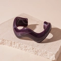 Macro detail of purple marbled acrylic wavy open bangle on a natural stone surface - Purple