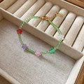Dettaglio dei ciondoli a fiore in cristallo colorato e perline verdi su collana dorata - Bracciale fiore di cristallo verde