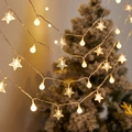 Warm white LED star and globe string lights hanging against a festive tree background - Spheres + Stars (warm Colors) / 1.5m 10LED Battery
